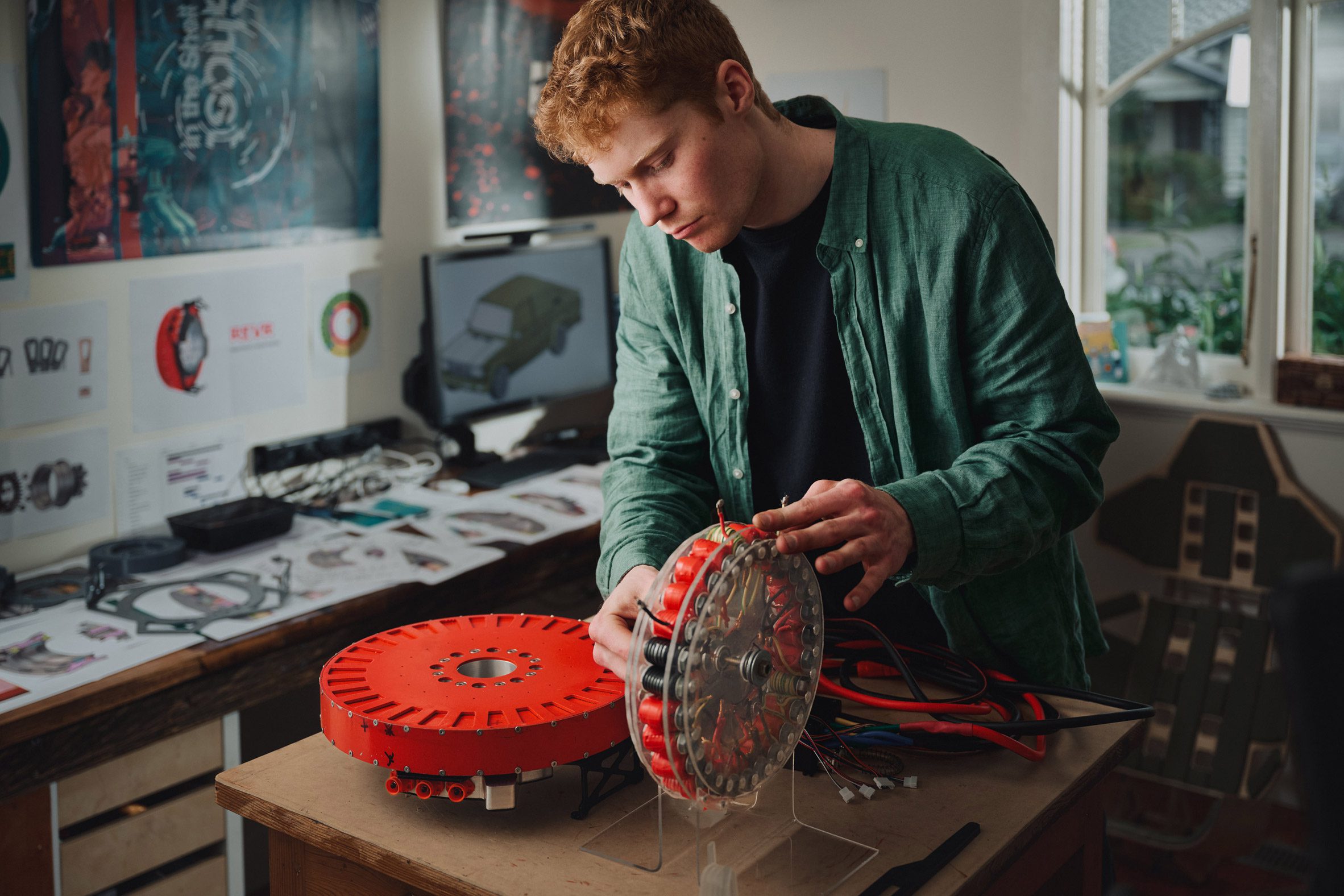 Photo of designer Alexander Burton tinkering with two disc-shaped prototypes that form his REVR invention