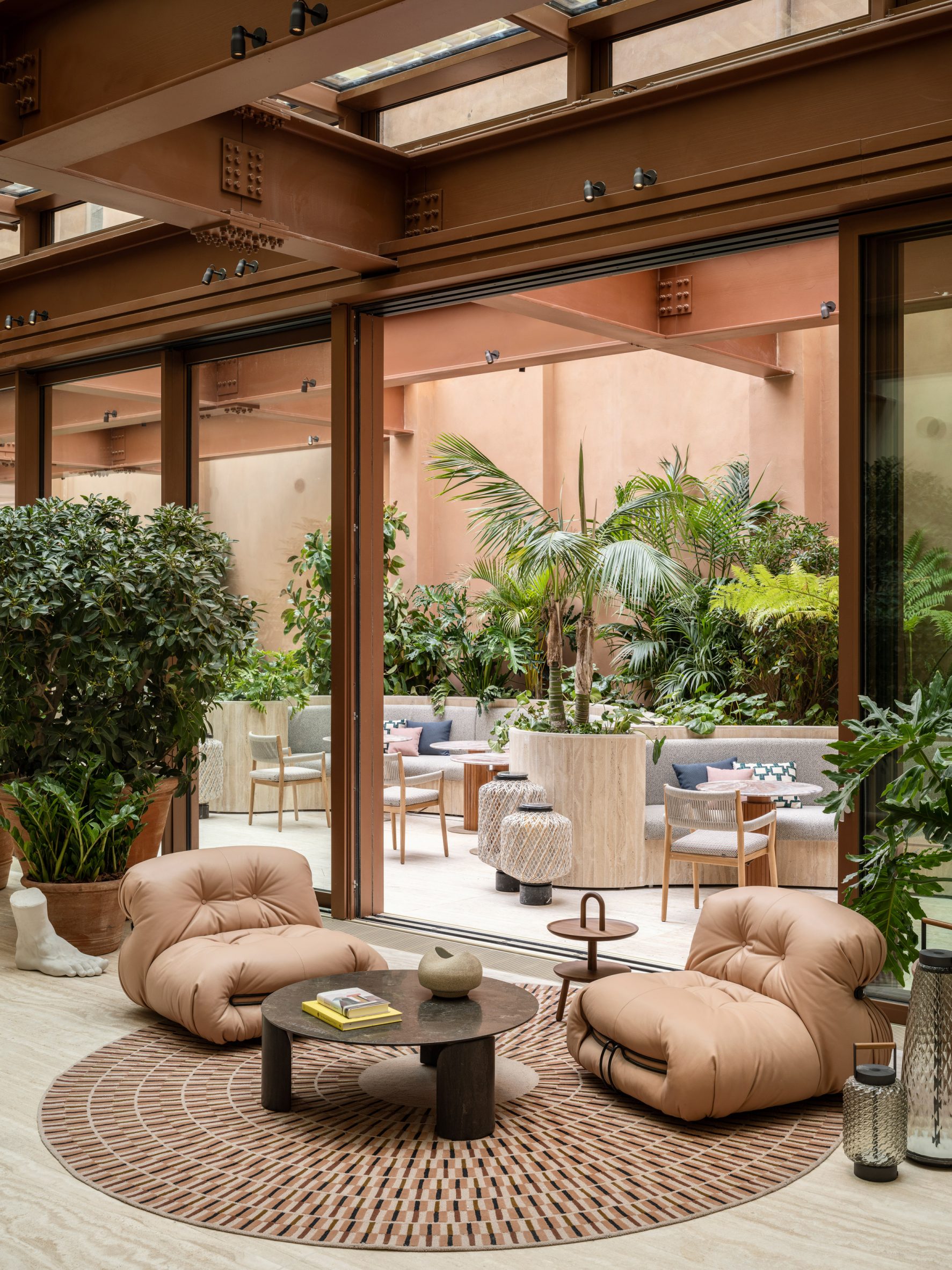 Lounge seats on a circular rug, in front of an opened glass partition in Six Senses Rome hotel by Patricia Urquiola