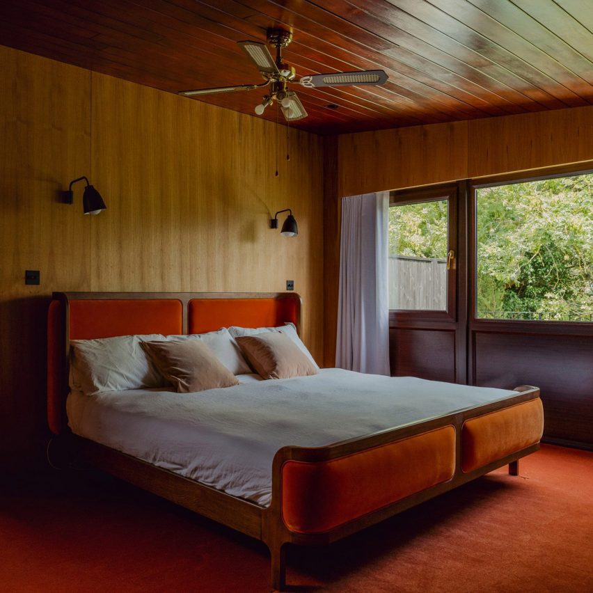 Bedroom in Zero House with wood-panelled walls and an orange carpet