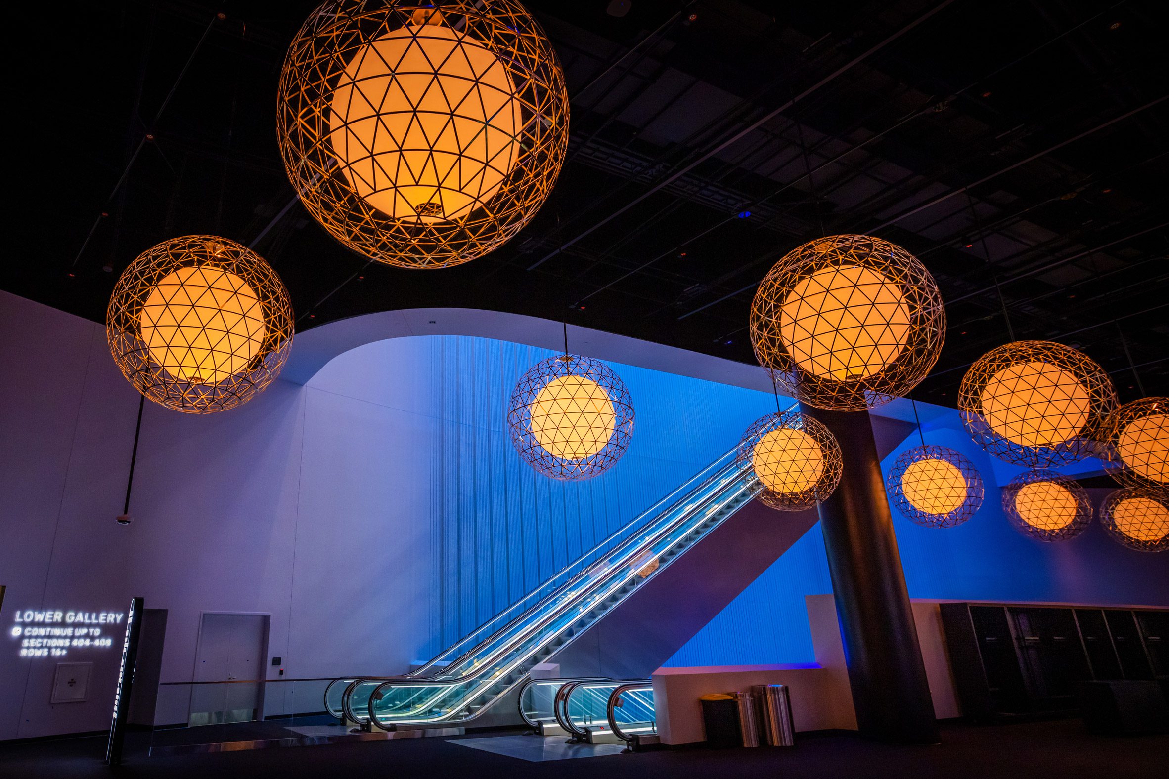Scrim wall behind an escalator bank, with spherical pendant lights in the foreground
