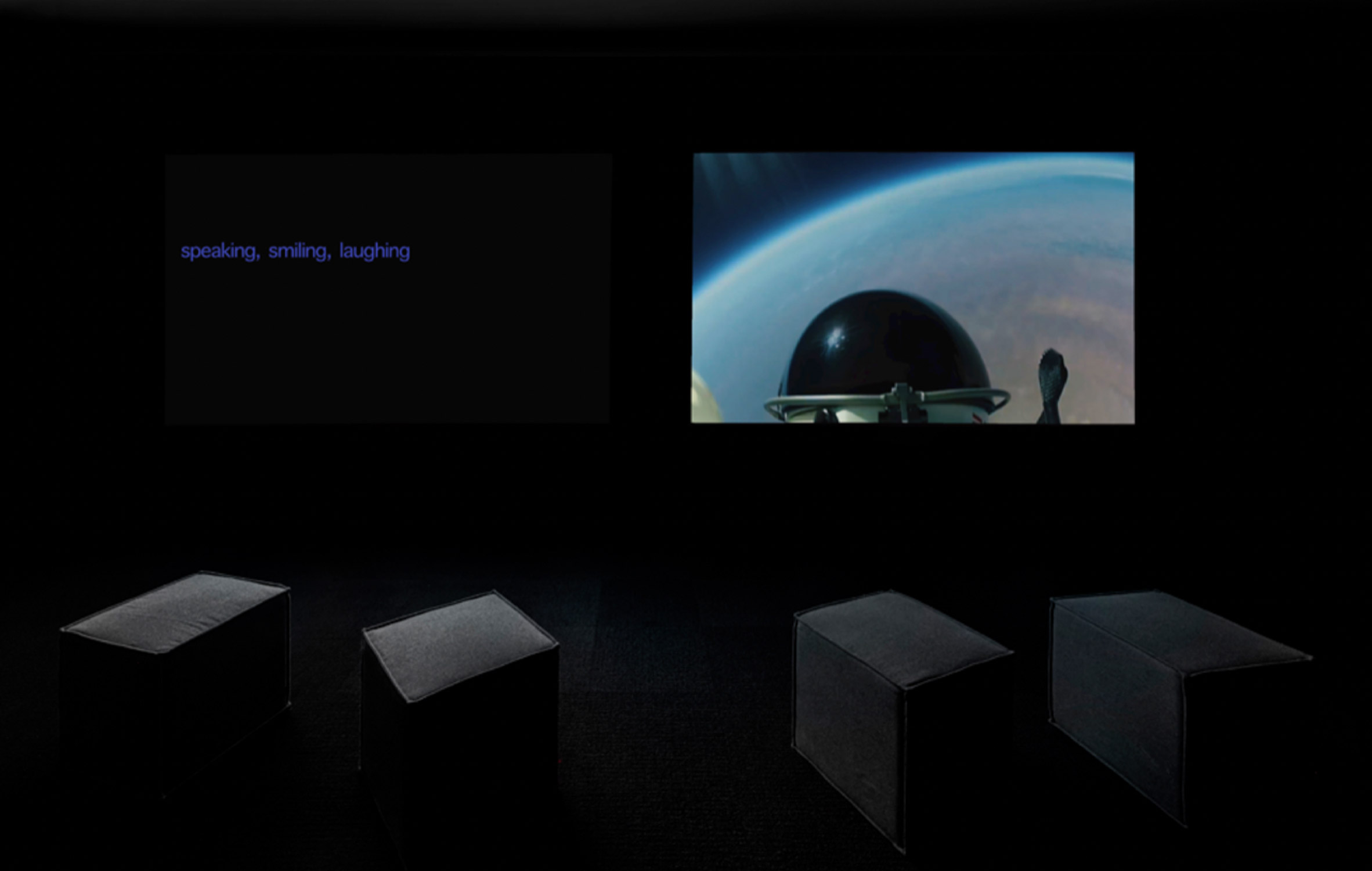 Photo showing stools in front of two screens in a dark space