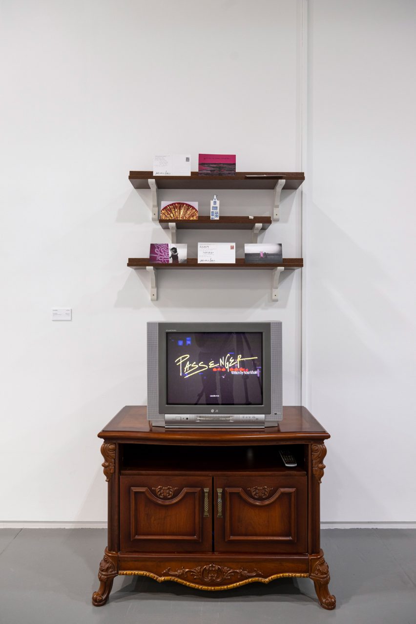 Photograph showing a television on a cupboard beneath some shelves in an exhibition space