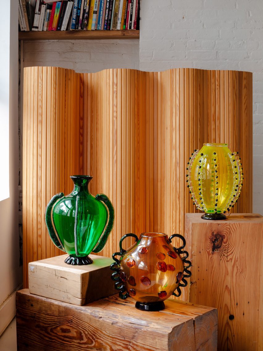 Three glass vases shaped like vegetables on wooden stands