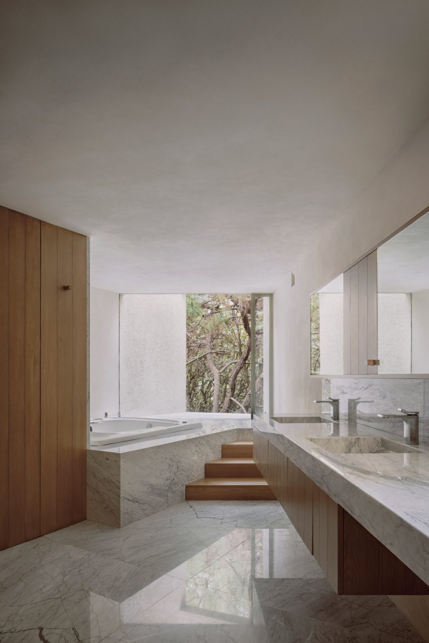 Bathroom with marble surfaces and a window overlooking the forest
