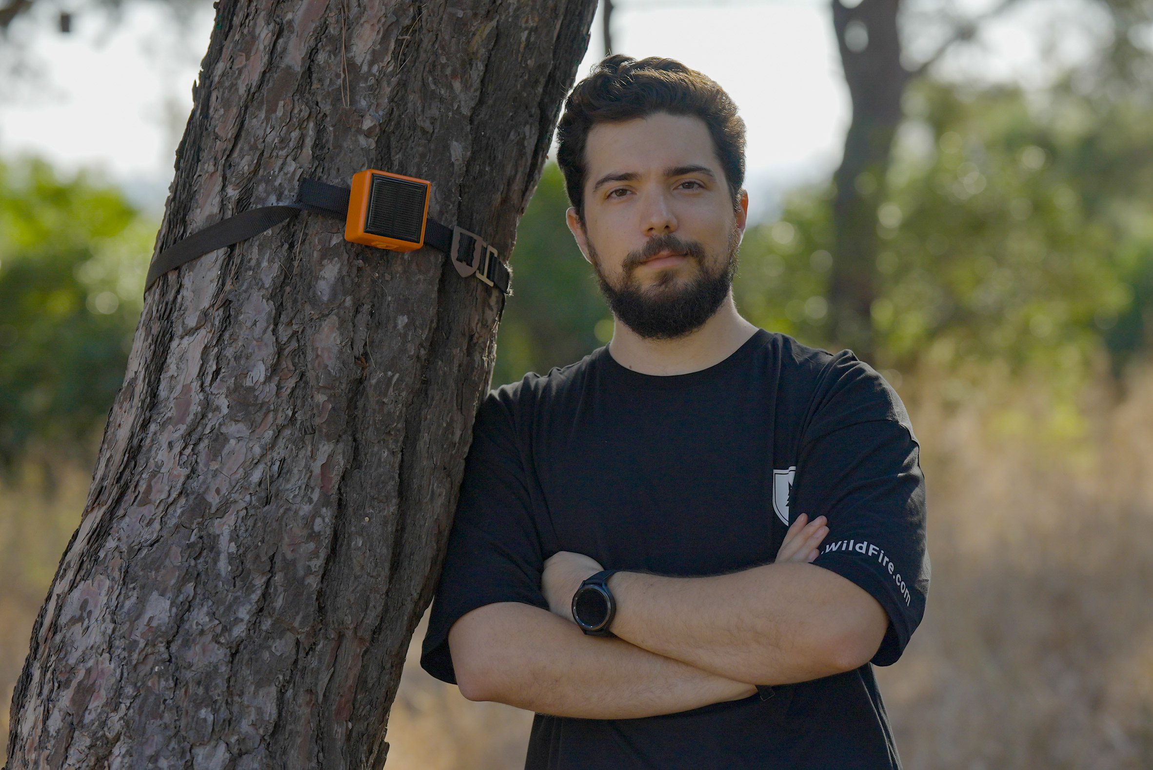 Photo of ForestGuard CTO Suat Batuhan Esirger leaning against a tree to which a ForestGuard sensor module is attached