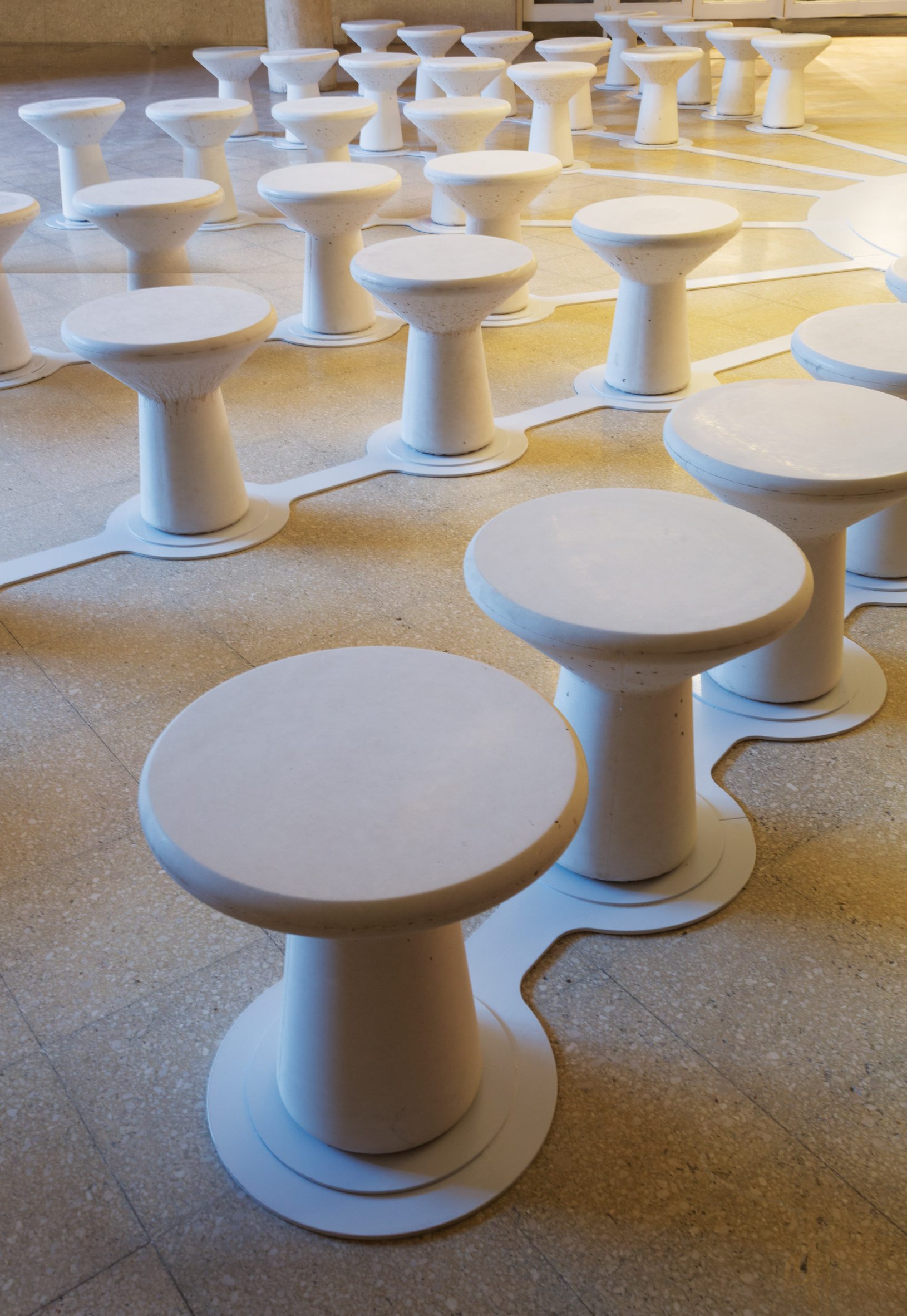 Lines of white concrete stools arranged to form concentric rings