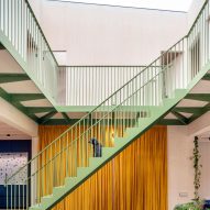 Green-painted metal staircase in a plywood-panelled atrium
