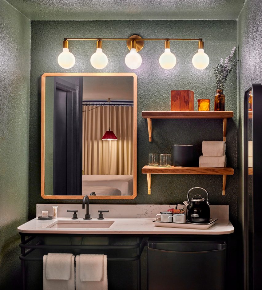 Dark green bathroom with lighting above a mirror, shelves and sink