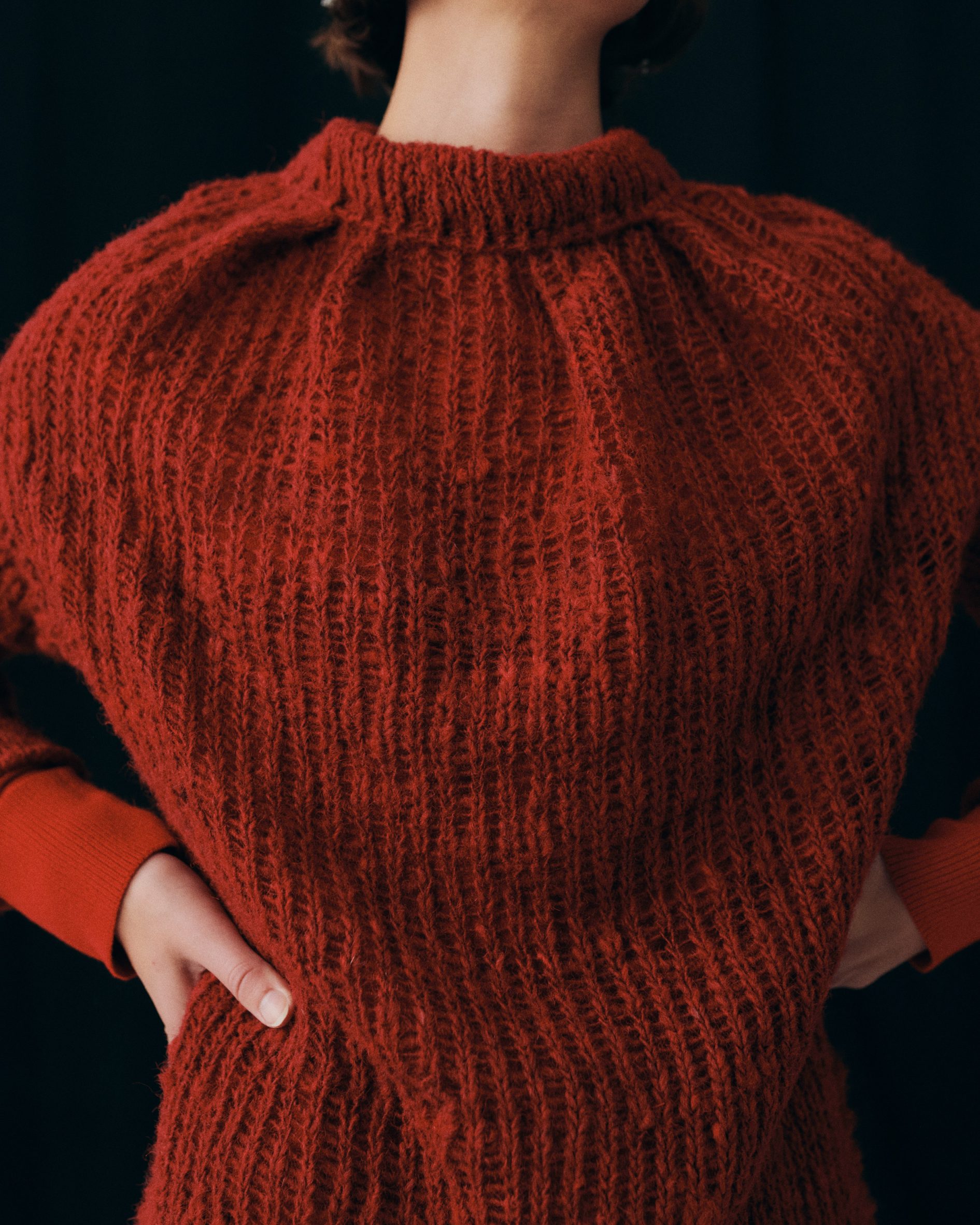 Photo of a woman's torso wearing a deep red knit sweater