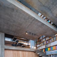 Floating concrete stairs on a bookshelf wall in a concrete home