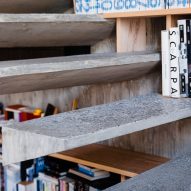 Floating concrete stairs on a bookshelf wall