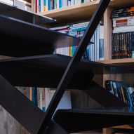 Black metal staircase next to bookshelves