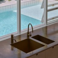 Kitchen sink by a window overlooking an outdoor swimming pool