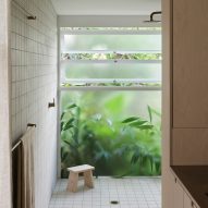 White-tiled bathroom with frosted windows next to planting