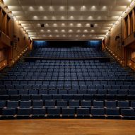 A theatre with blue seating and wooden paneling