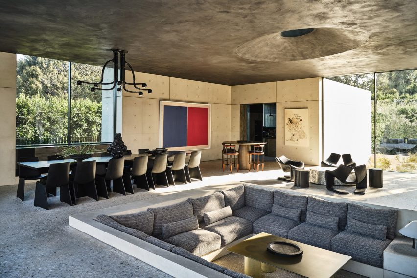 Large room with a conversation pit and dining table below a black plaster ceiling