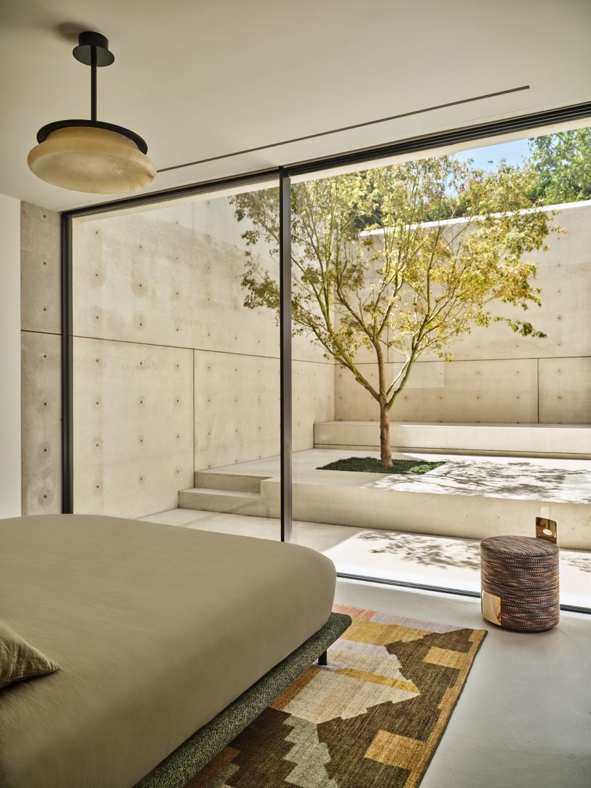 Bedroom facing a concrete courtyard with a single tree