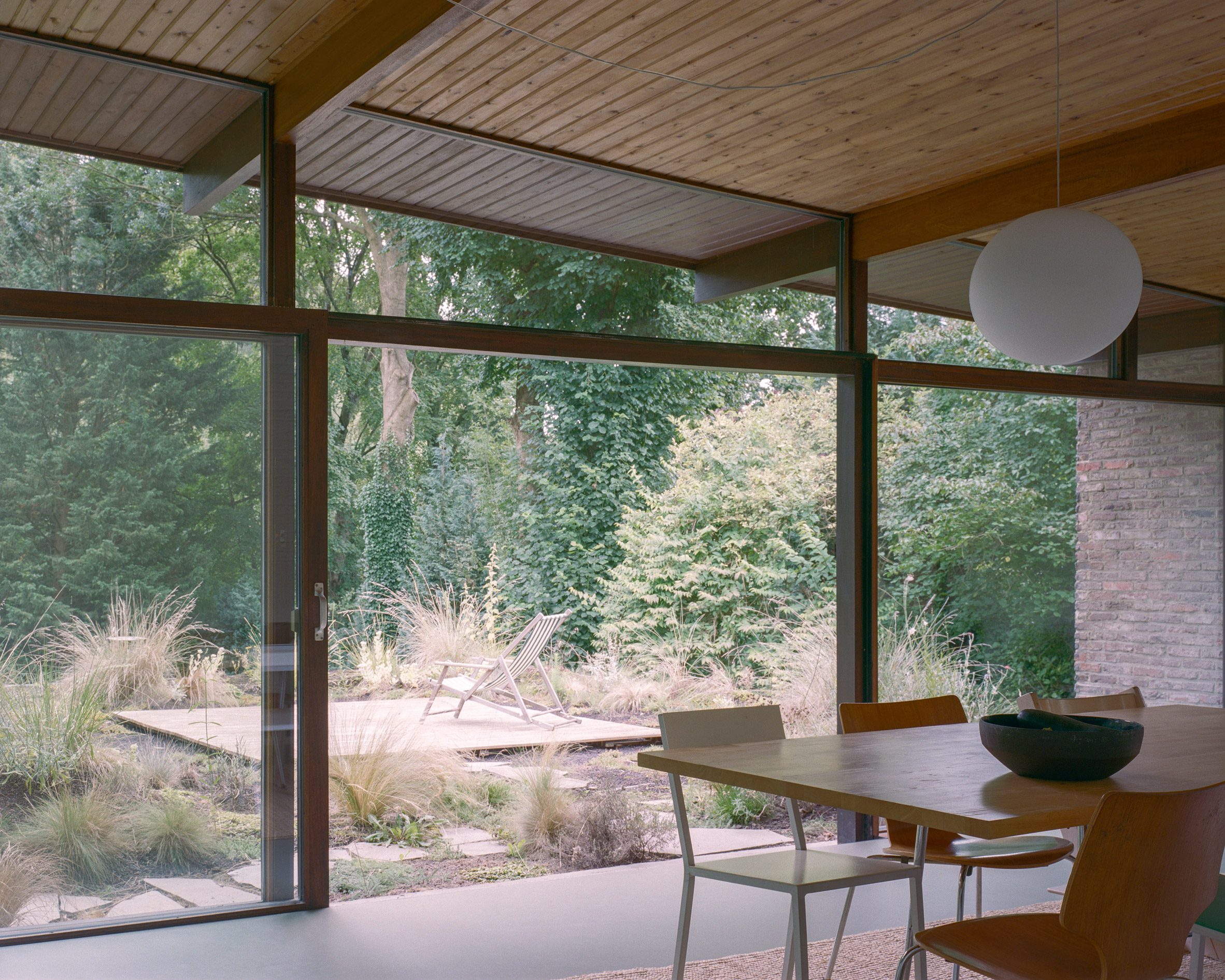 Open-plan dining room with a timber-framed glazed facade overlooking a garden