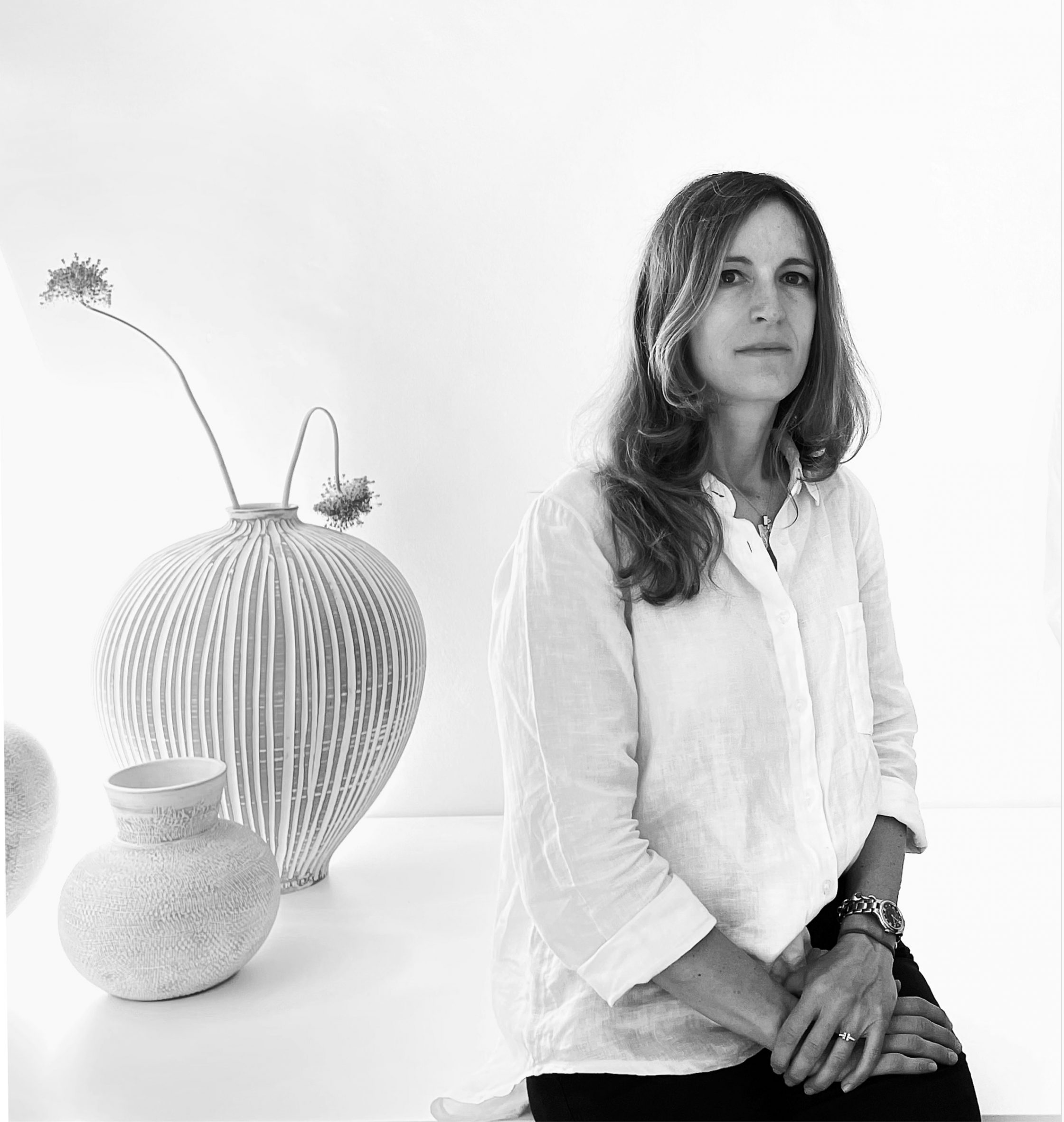 Black and white portrait of Elisa Vago with vases in the background