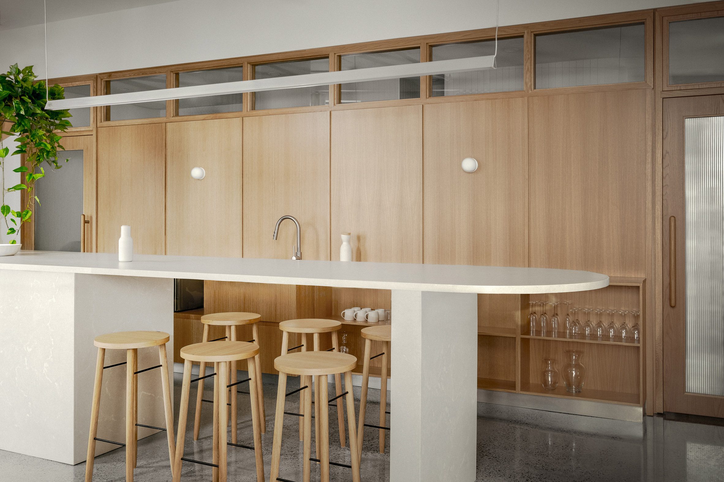 Communal kitchen with wood-panelled wall and a central concrete island