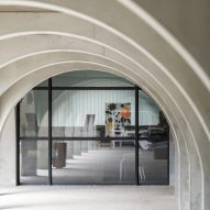 Wide concrete archways in front of a glass building