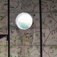Circular window opening and painted flowers on concrete wall