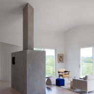 A large concrete fireplace in a white house with curved walls