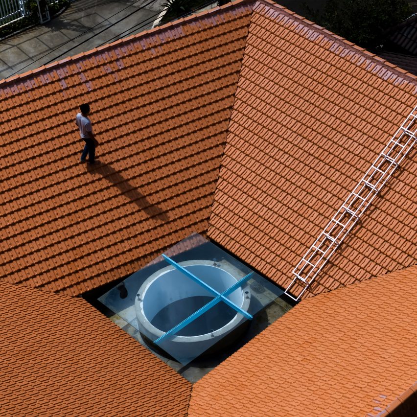 Person walking on a red-tiled roof on a home by The Bloom Architects