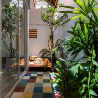 Interior with planting and multi-coloured square floor tiles at Tile House by The Bloom Architects