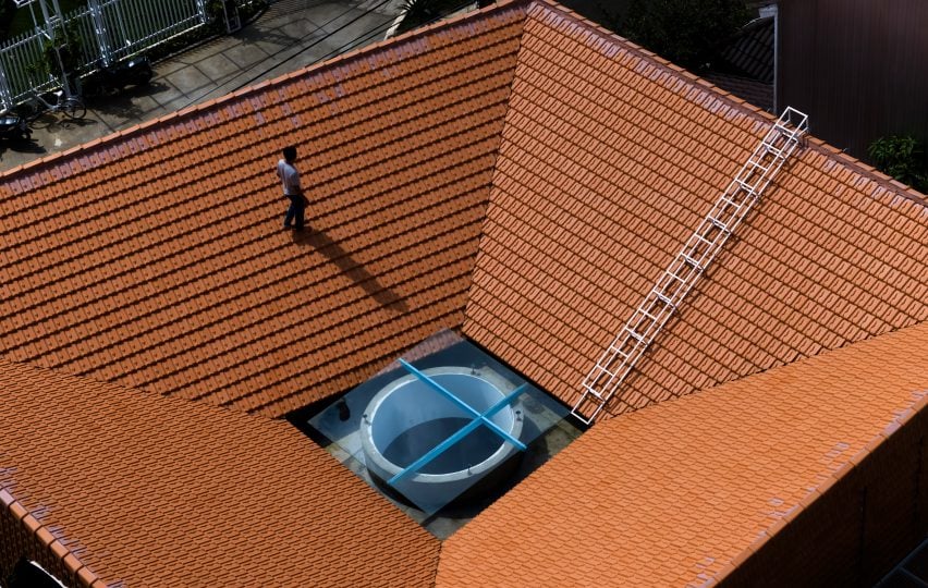 Person walking on a red-tiled roof on a home by The Bloom Architects