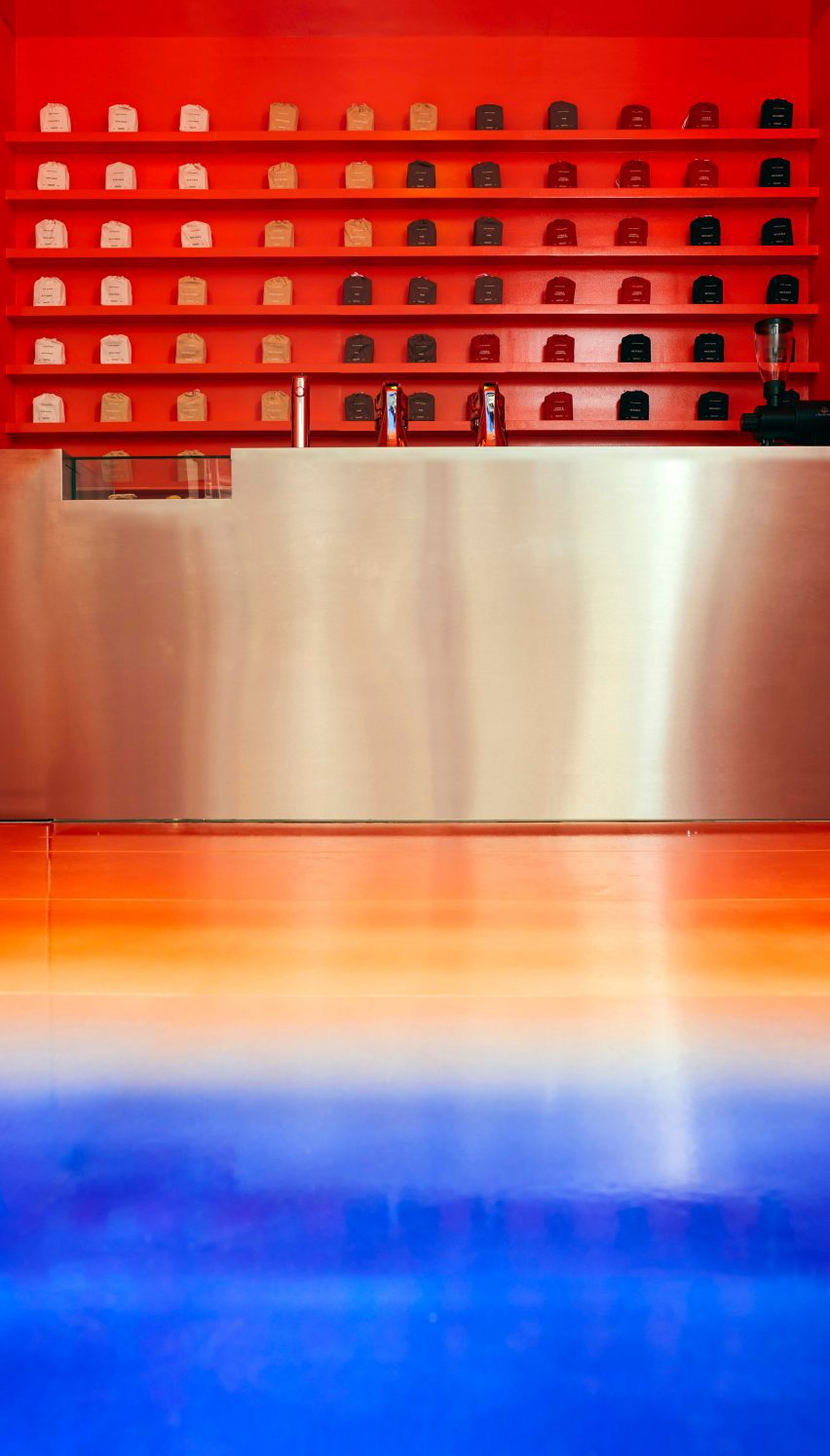 Stainless steel counter with orange lacquered shelving behind it