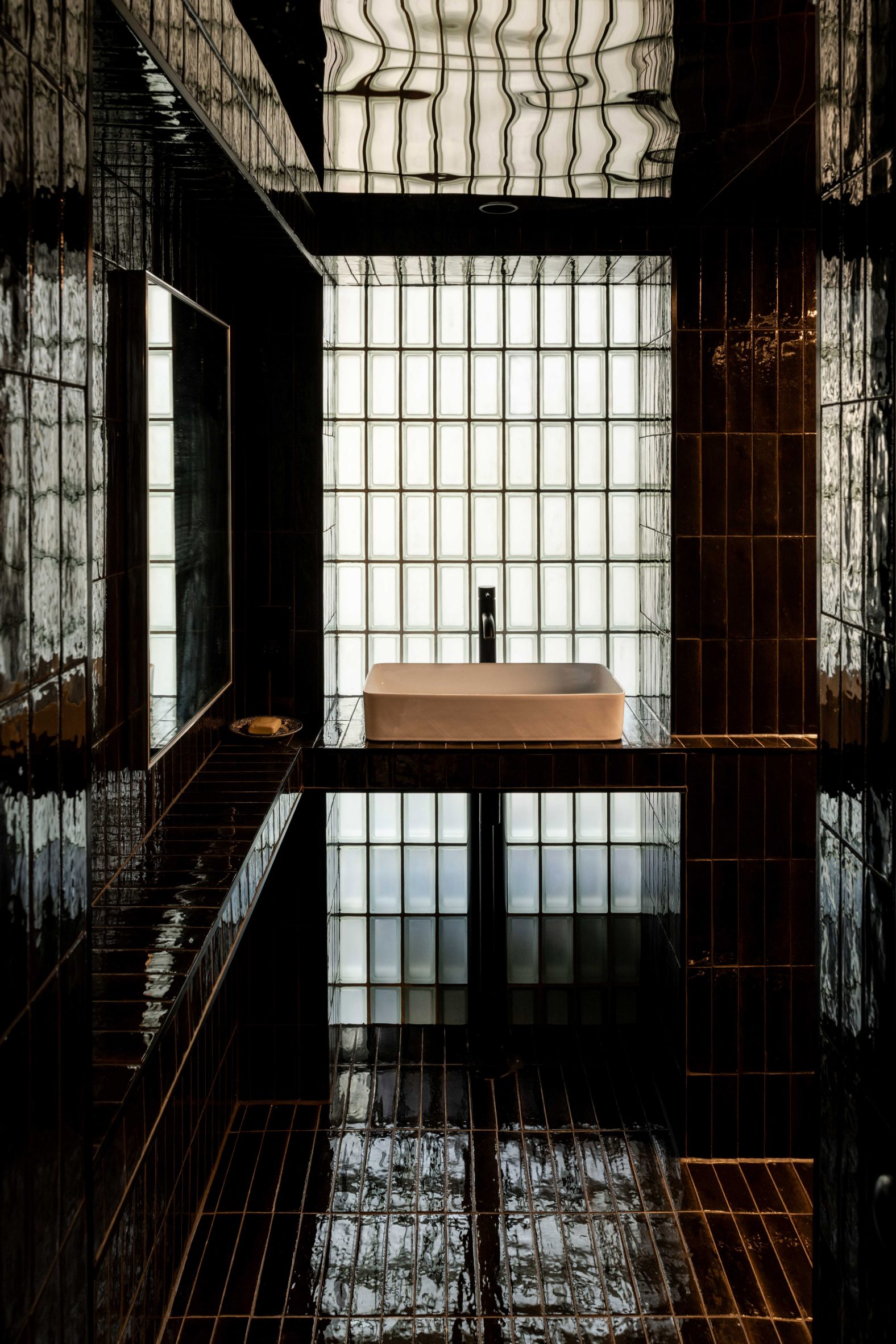Black-tiled bathroom of Walden apartment by Polysmiths