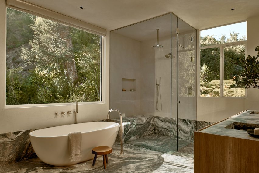 Bathroom with stone floor, freestanding tub and corner s،wer