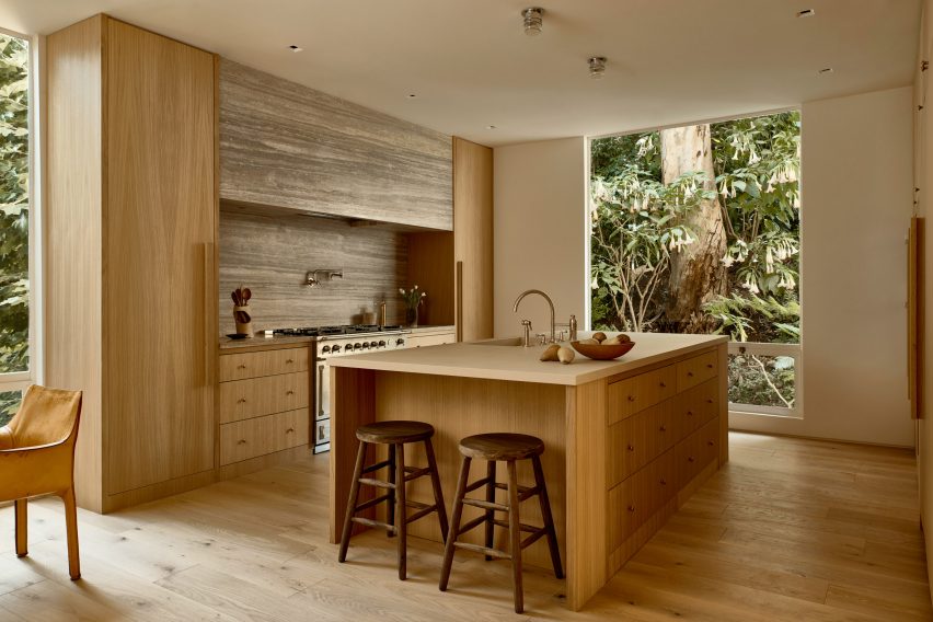 Kitchen with white oak island and cabinetry, and travertine backsplash