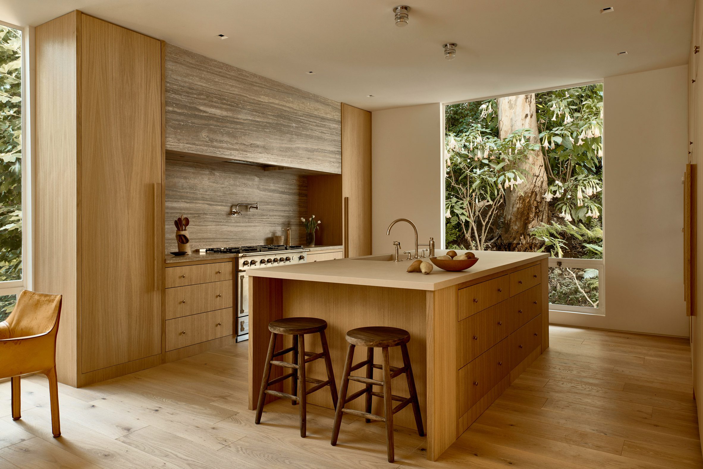 Kitchen with white oak island and cabinetry, and travertine backsplash