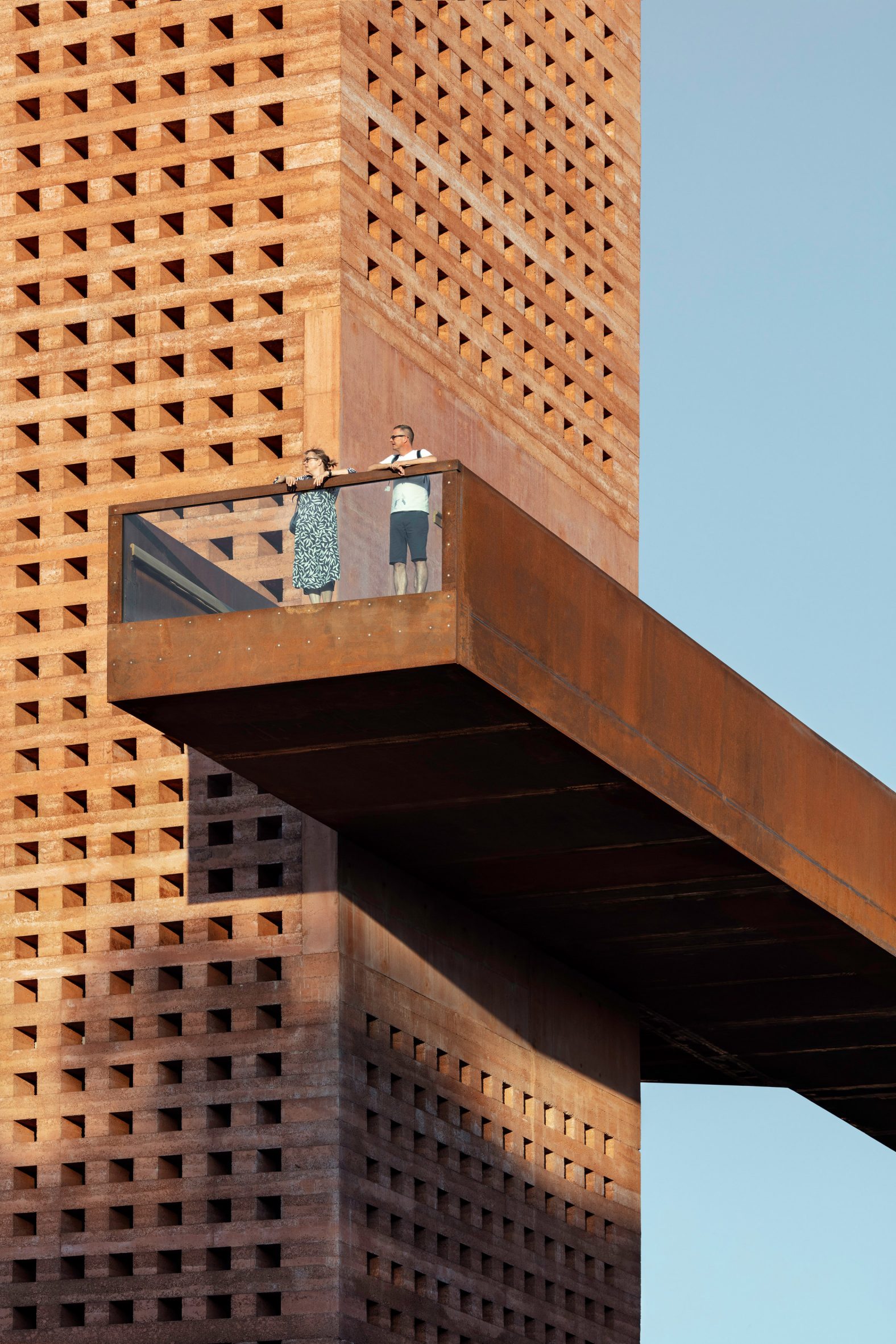 Exterior view of perforated tower and bridge by Mono Architekten