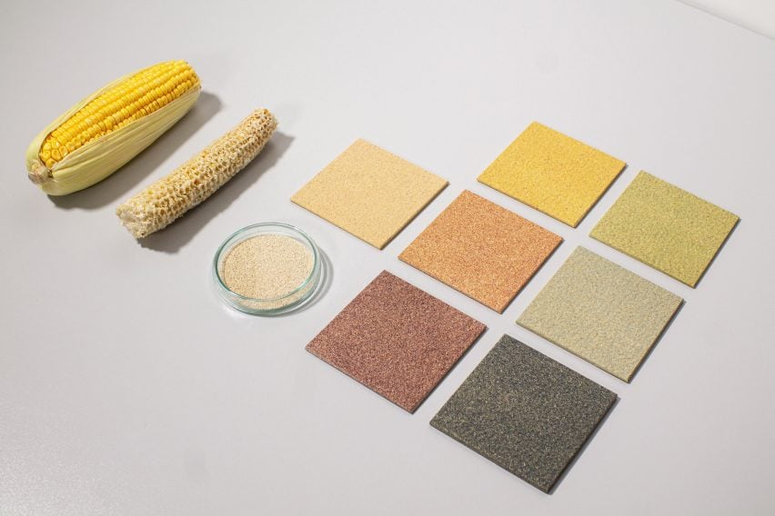 P،to of seven colours of CornWall tile in flatlay, ranging from a warm beige to a a muted reddish brown and a dark greenish grey. The tiles are arranged beside a bare corn cob, a full corn cob and a small bowl of shredded biom،