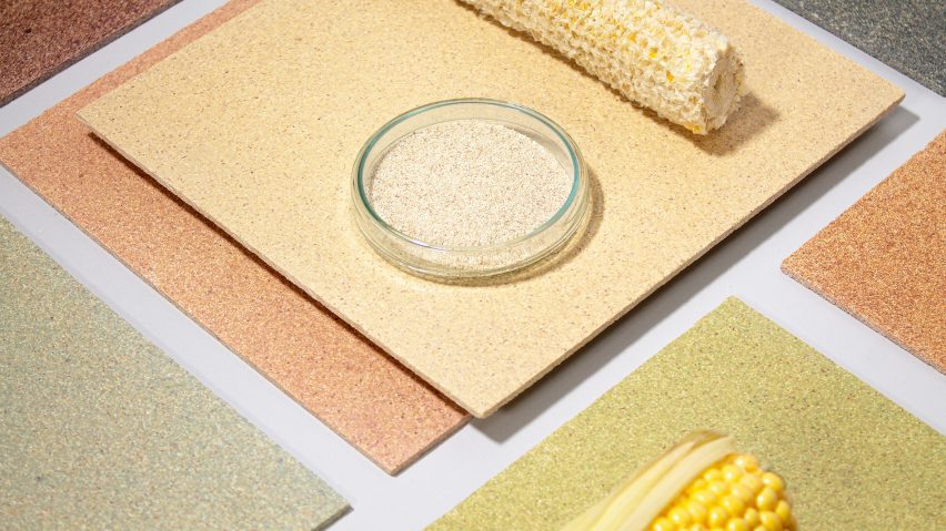 Photo of a flatlay of CornWall tiles by Circular Matters and StoneCycling in several muted, natural colours, arranged with a bare corn cob, a full corn cob with some of the husk on it and a small bowl of pale shredded organic material