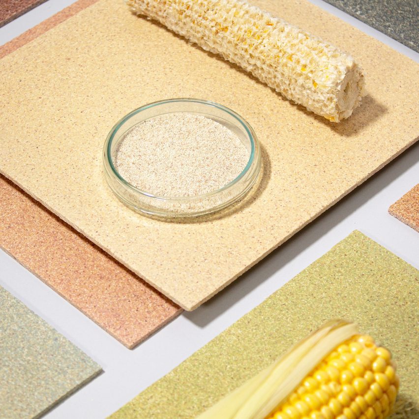 Photo of a flatlay of CornWall tiles by Circular Matters and StoneCycling in several muted, natural colours, arranged with a bare corn cob, a full corn cob with some of the husk on it and a small bowl of pale shredded organic material