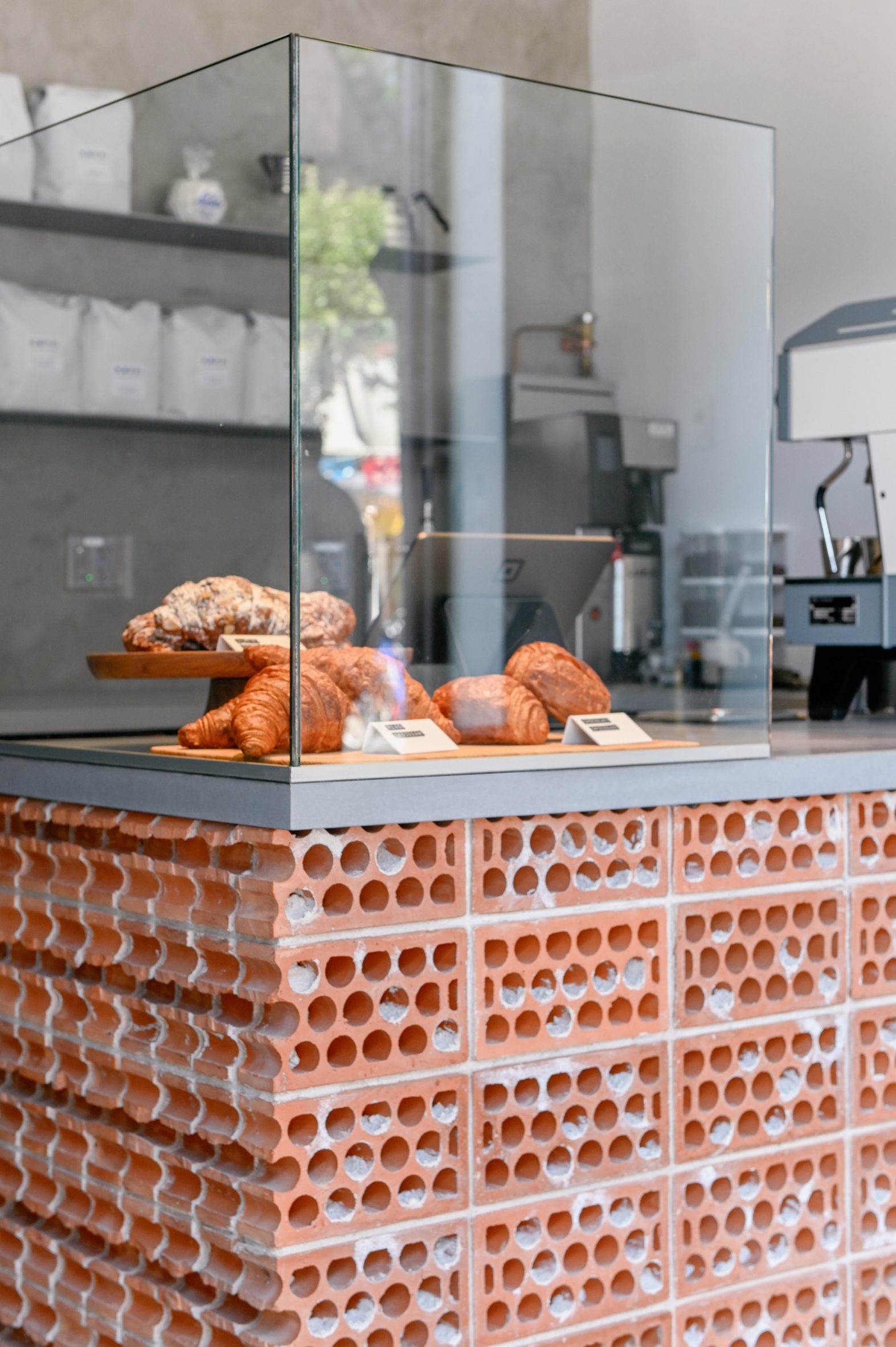 A counter terminated by a course of cut bricks, with a glass enclosure for pastries on top