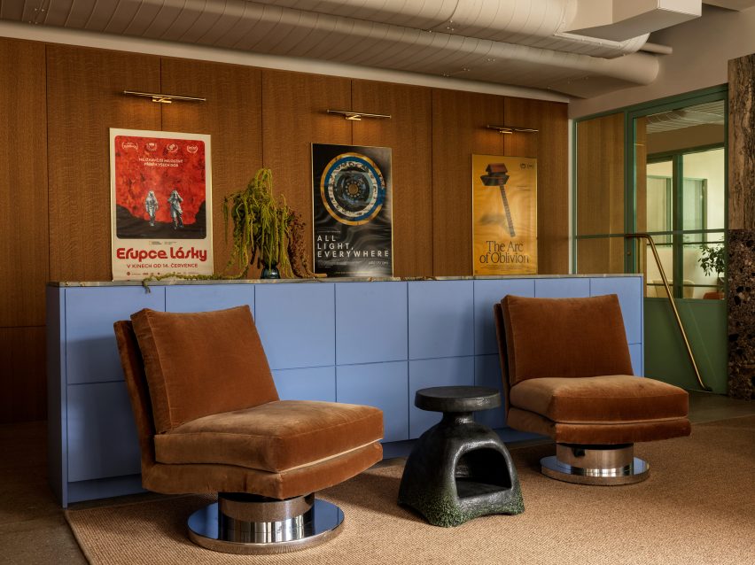 Swivel chairs in front of a periwinkle blue divider, with film posters behind