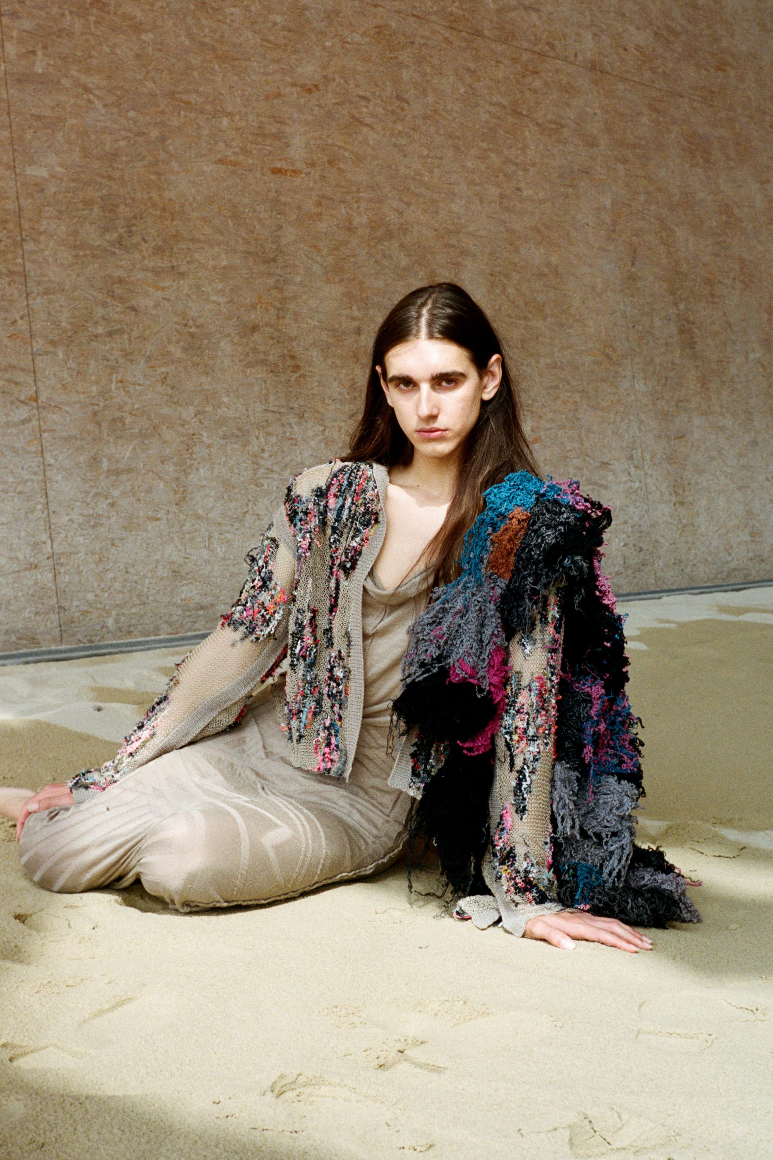 Seated model wearing multicoloured, shaggy garments