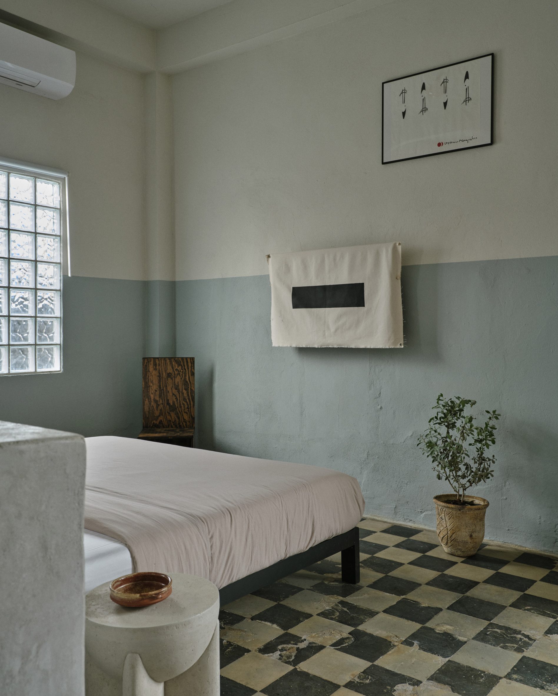 Studio apartment with vintage floor tiles, central bed and blue-beige walls