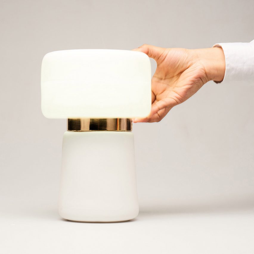 a modern table lamp and a hand holding it on the right side