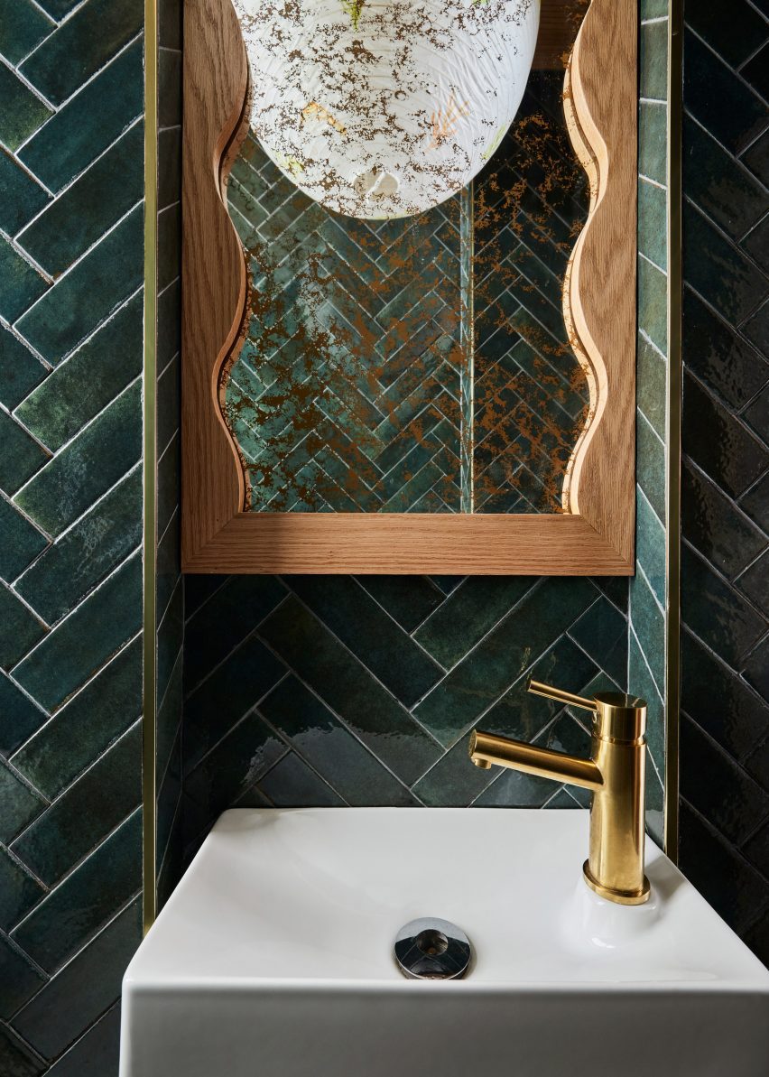 Bathroom featuring dark green tiles and a hand-painted rice paper pendant light