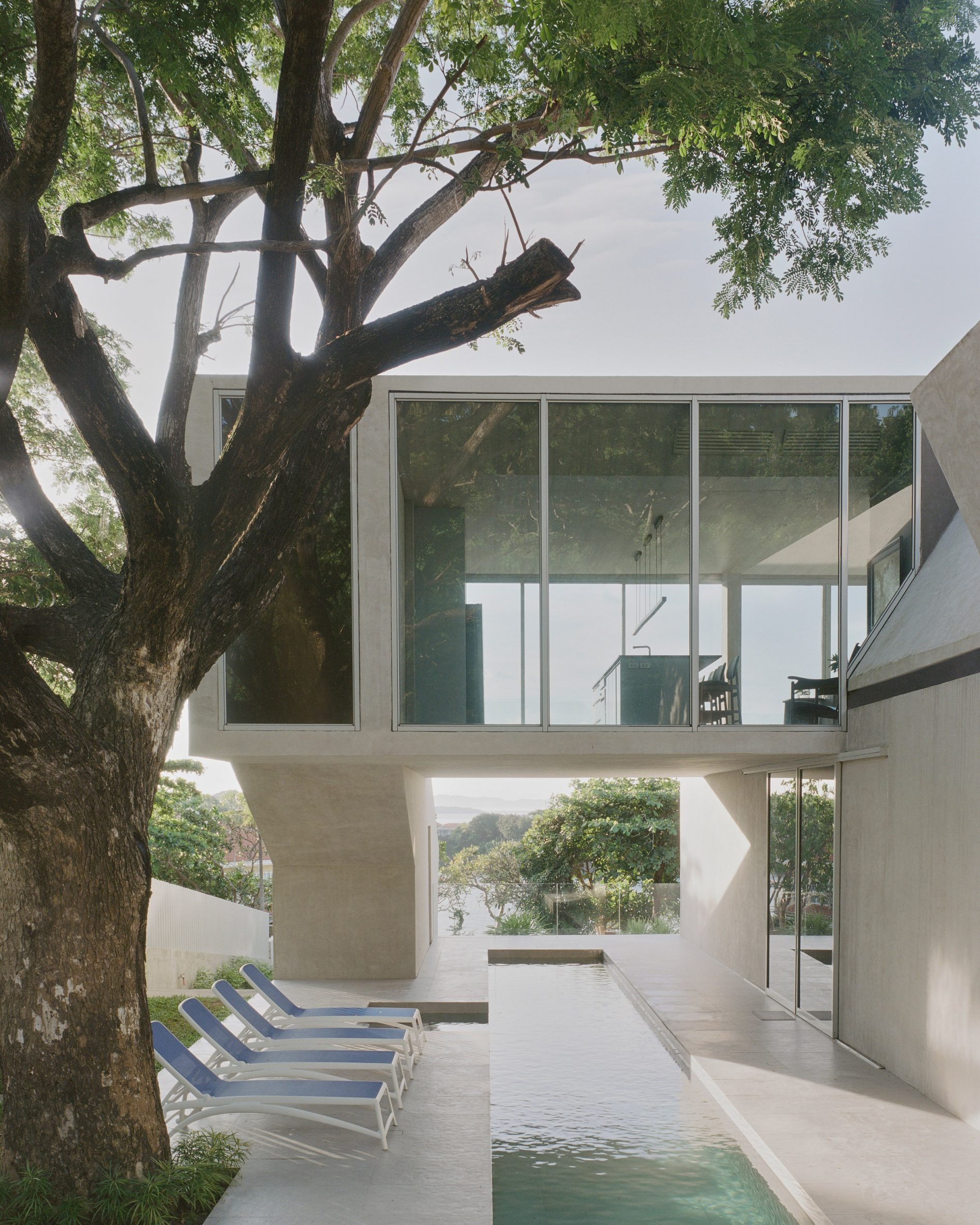 Glazed upper floor oversails swimming pool in FR House in the Philippines by CAZA