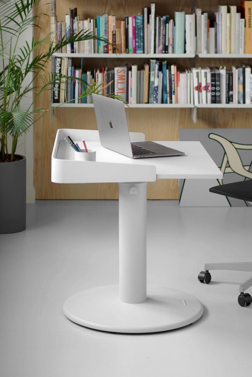 A laptop sits on a white square table with a circular base