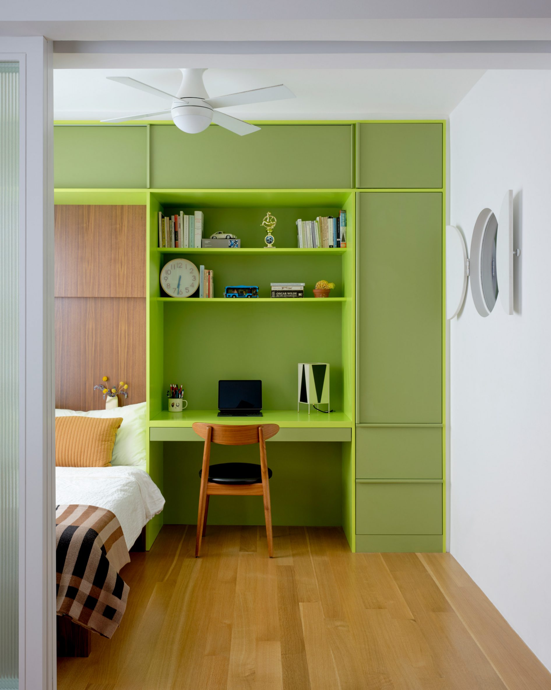 Bedroom with lime green built-ins housing a bed, a desk and storage