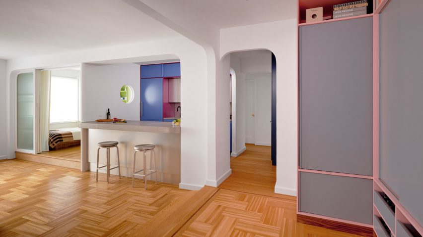 Wide view of an apartment with wooden floors, white walls and colourful accents