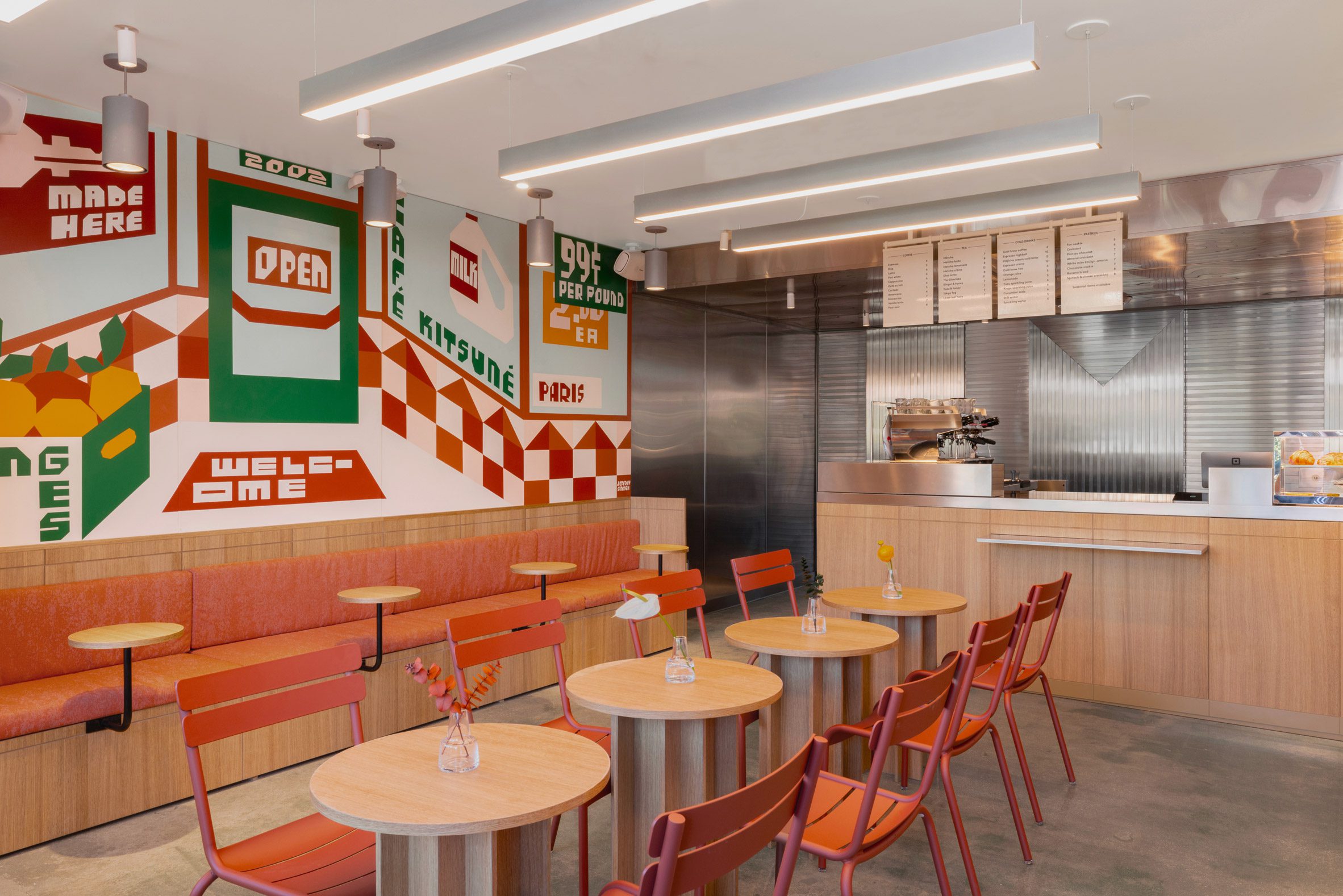 Cafe interior with white oak tables, burnt orange seats and a wall mural